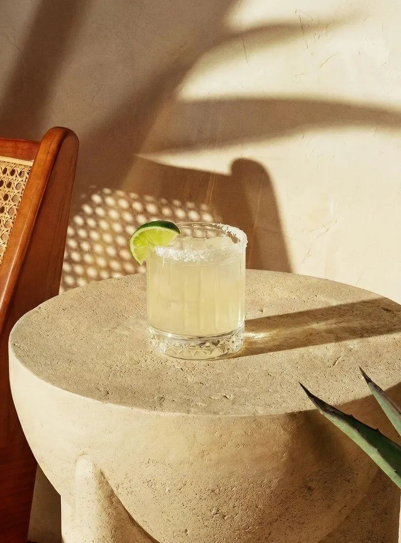 A short glass with lime on a stone table in late afternoon light